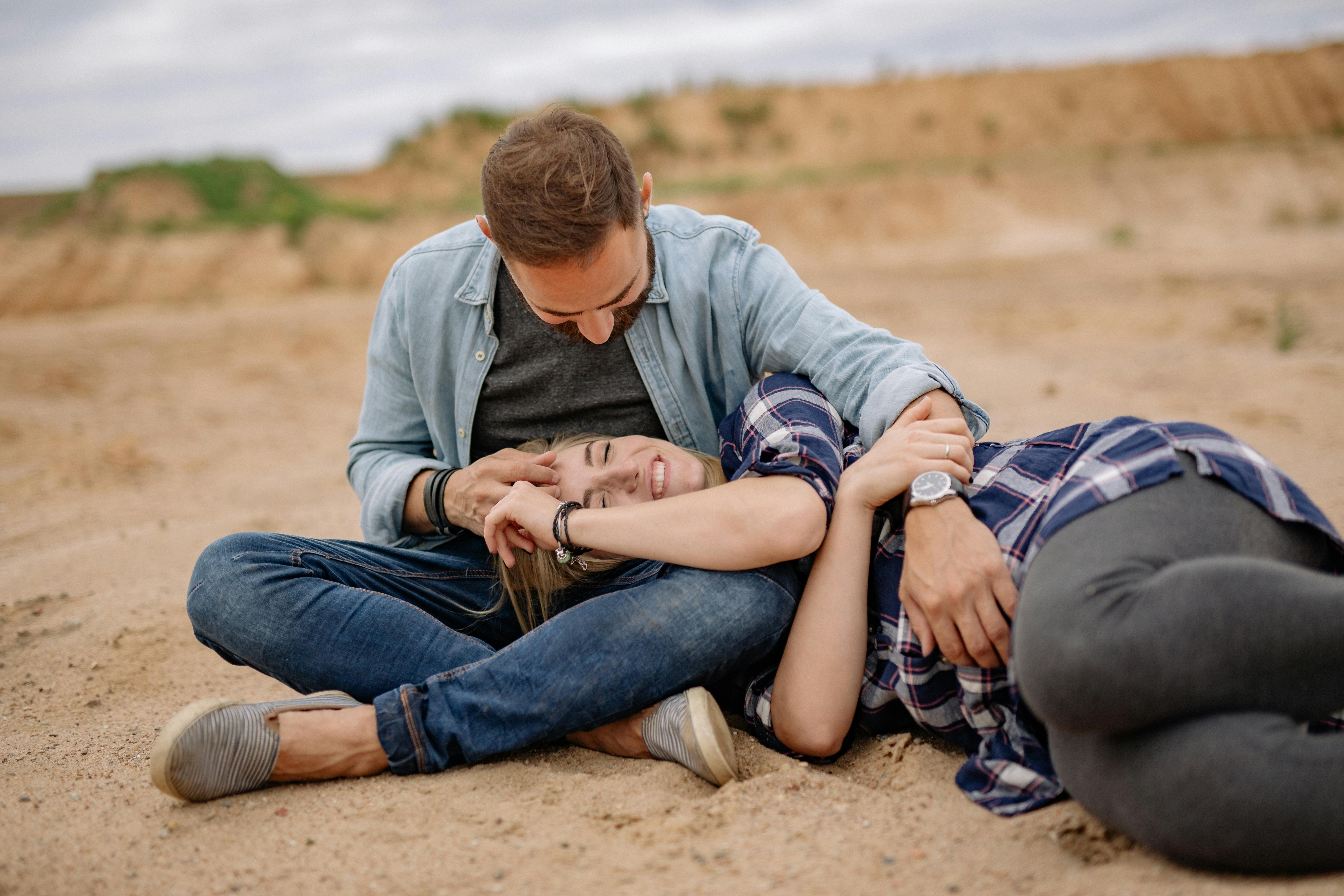 Man Sitting on Sand while Woman Lying on his Lap · Free Stock Photo