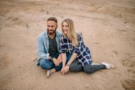 Man and Woman Sitting on Brown Sand