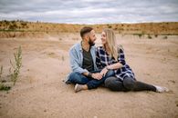 Couple Sitting on Sandy Beach and Holding Hands