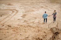 Man in Blue Shirt Walking on Brown Sand