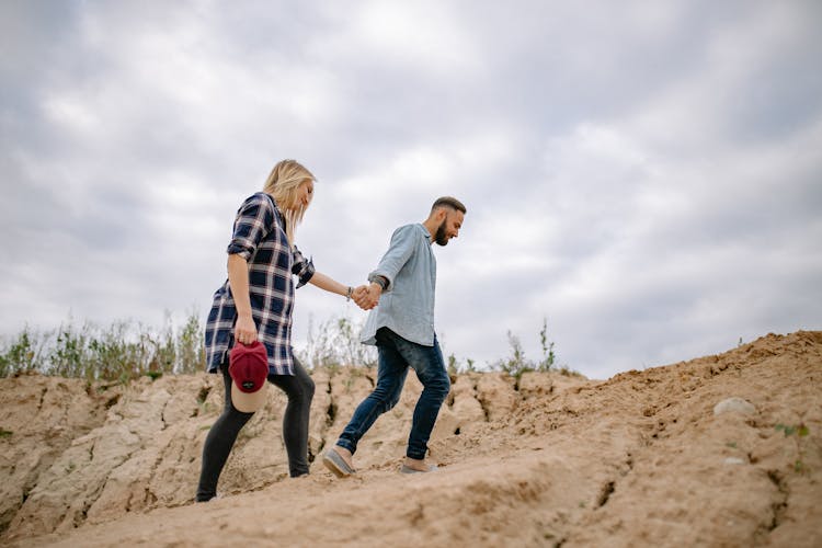 Man Leading Woman By Hand Across Sand Dunes