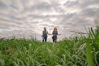 Happy Couple Running on Grass Field