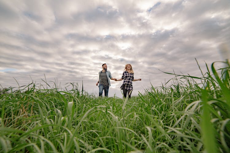 Happy Couple Running On Grass Field