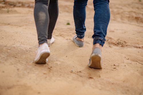 Free A couple walks casually on a sandy path, showing footwear and lower legs. Stock Photo