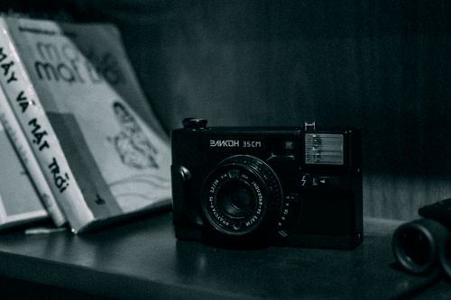 Free Black and white old bookshelf with paper books and small analog photo camera at home Stock Photo