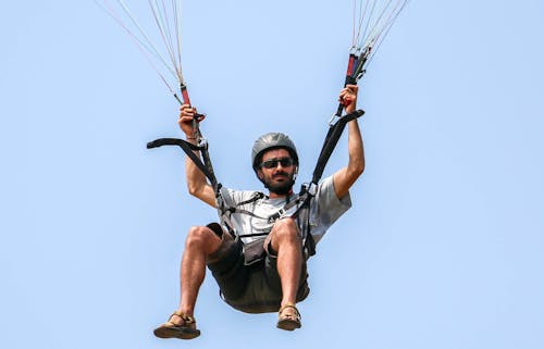 Man in White Shirt and Black Shorts Riding on Black and White Parachute