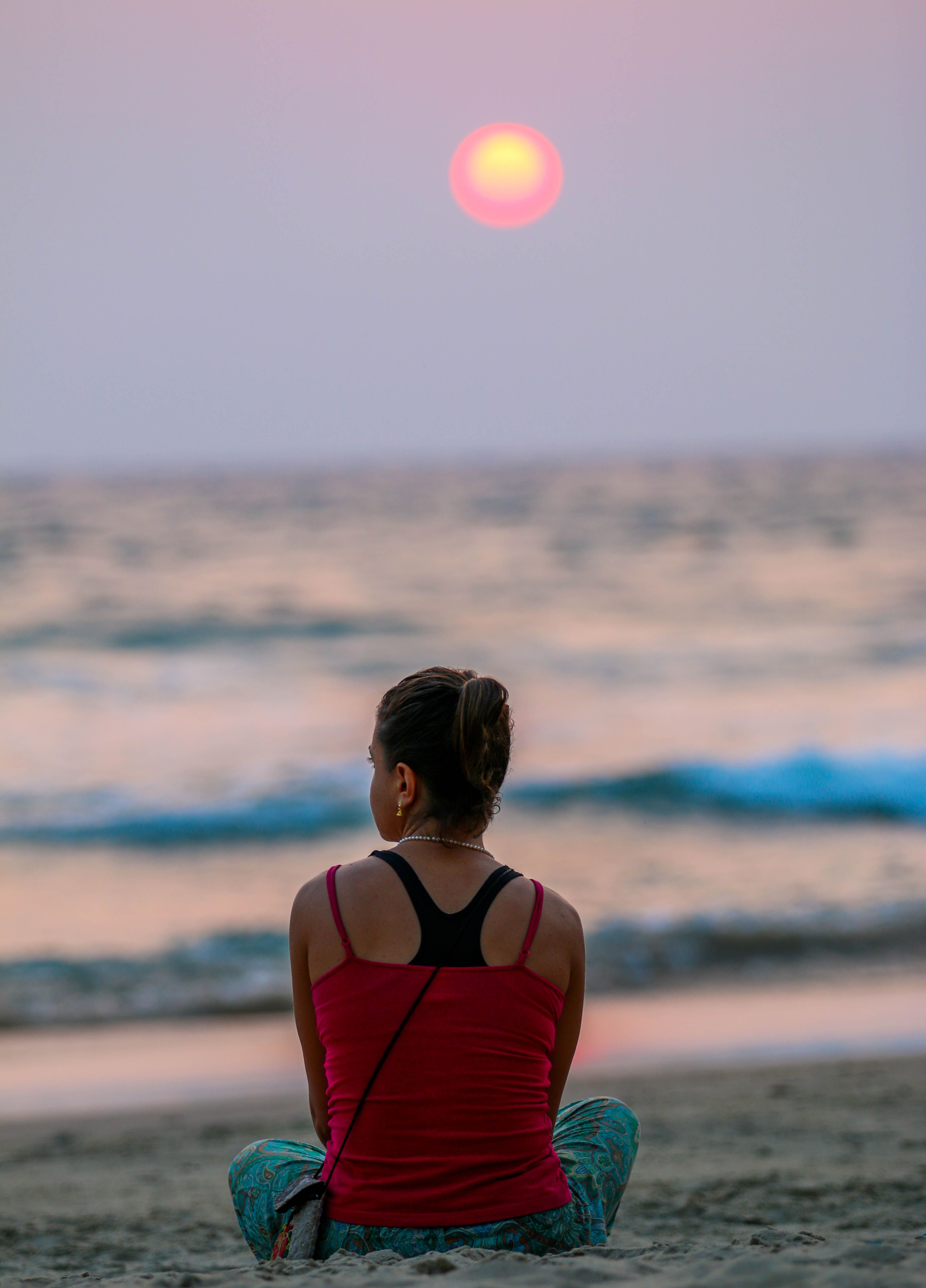 A Woman in Red Tank Top Sitting on Beach during Sunset · Free Stock Photo