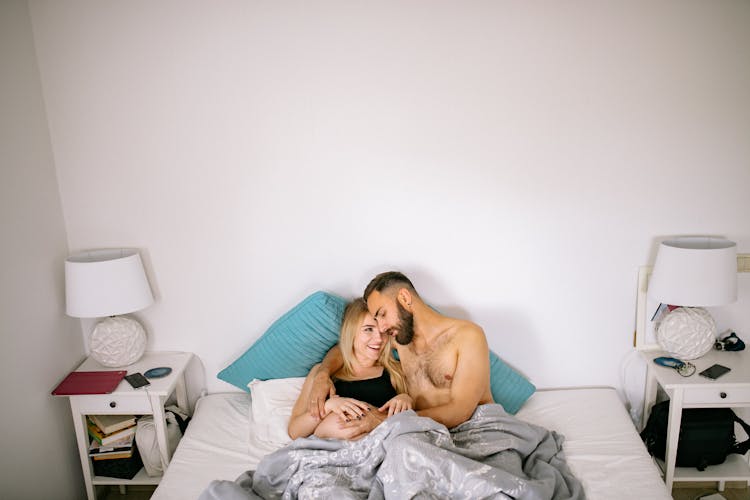 Man Touching Pregnant Woman Belly Cuddling In Bed