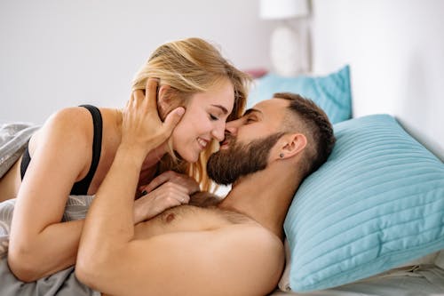 Shirtless Man Holding Woman's Neck while Lying on Bed