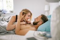 Woman in Black Tank Top Lying on Bed Beside Man in Blue Shirt