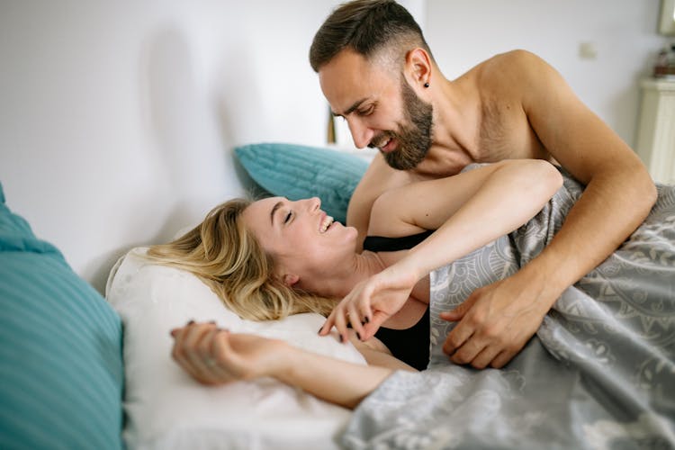 Couple Lying In Bed And Smiling 