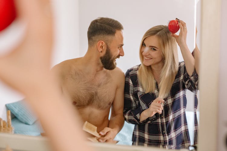 Happy Couple Looking In Mirror Brushing