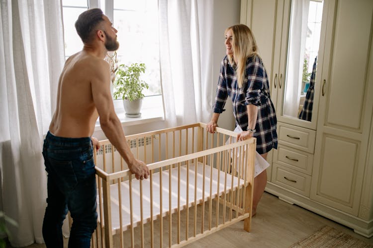 Happy Couple Assembling Baby Crib At Home