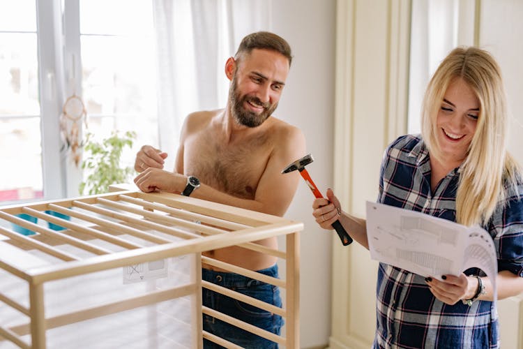 Man And Woman Building A Baby Crib And Smiling 