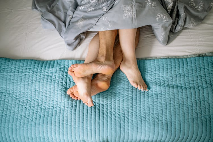 Close-up On Couples Legs Intertwined In Bed 