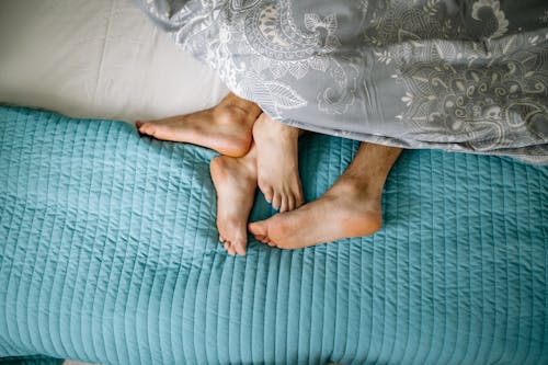 Close-up of Couple Legs Cuddling in Bed