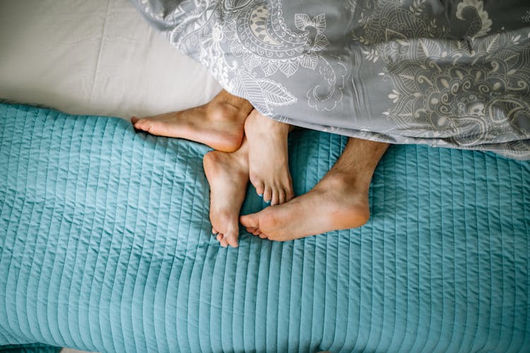 Close-up Of Couple Legs Cuddling In Bed