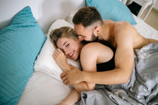 A happy couple embraces in bed, enjoying a relaxed morning together, capturing affection and happiness.