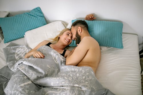 Free Couple Cuddling in Bed under Covers Stock Photo
