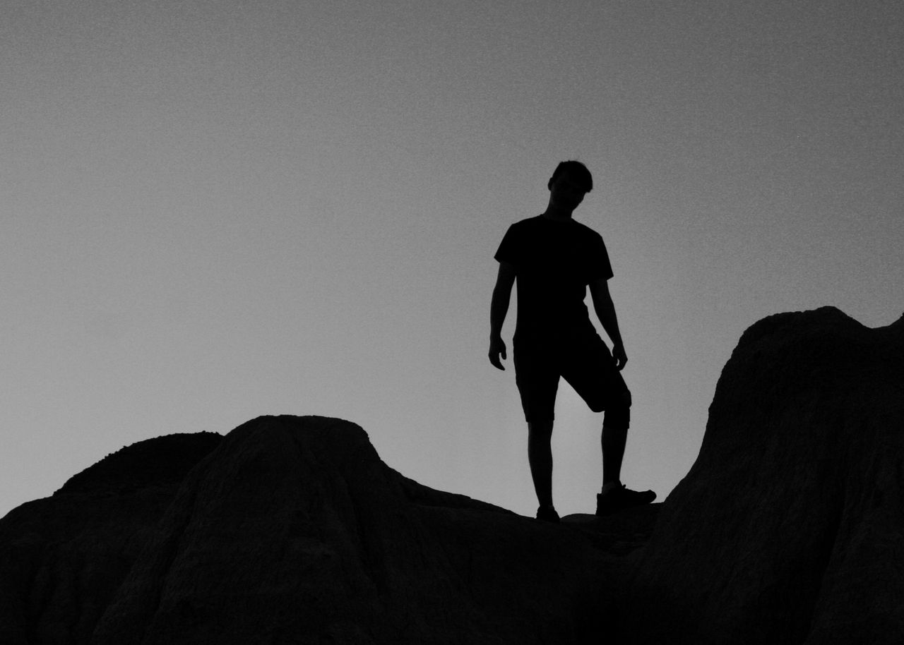 a silhouette of a man standing on rocks against a twilight sky offerin