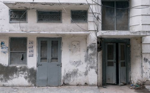 Free A decaying building facade with peeling paint and damaged windows in Faisalabad, Pakistan. Stock Photo