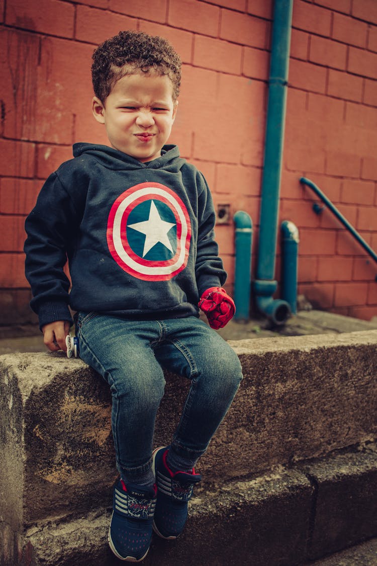 Cute Boy Sitting On Stone Border