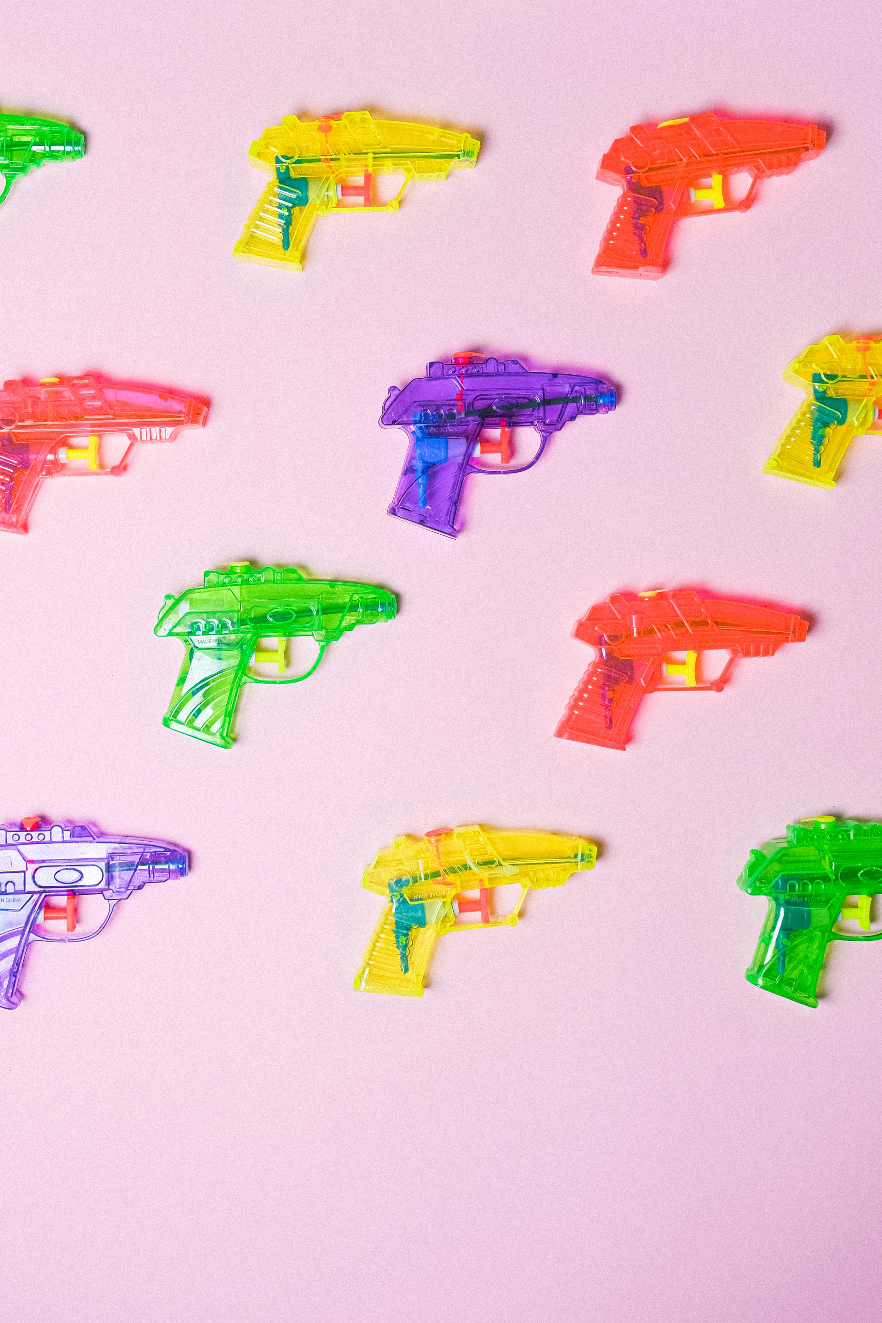 colorful guns in rows on pink surface