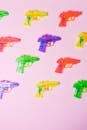 Colorful guns in rows on pink surface