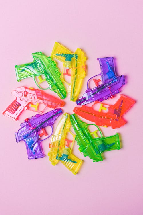 Top view of different colorful plastic toys arranged in circle on pink background