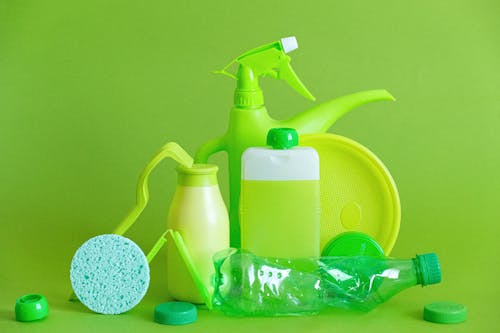 Monochrome green bottles and containers for liquids or gel with plastic bottle and lids on green background