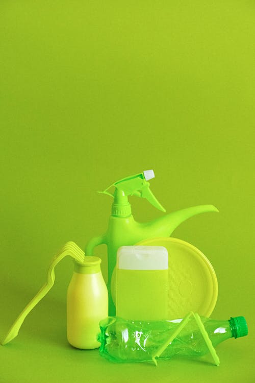 Free Set of assorted plastic containers for liquids with plate placed on green background Stock Photo