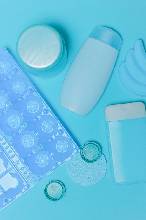 Top view of plastic bottles and egg tray with sponge and lids arranged on blue background