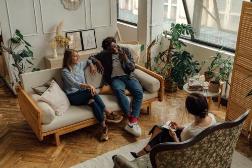 Free Three adults engaging in conversation in a stylish, plant-filled living room. Stock Photo
