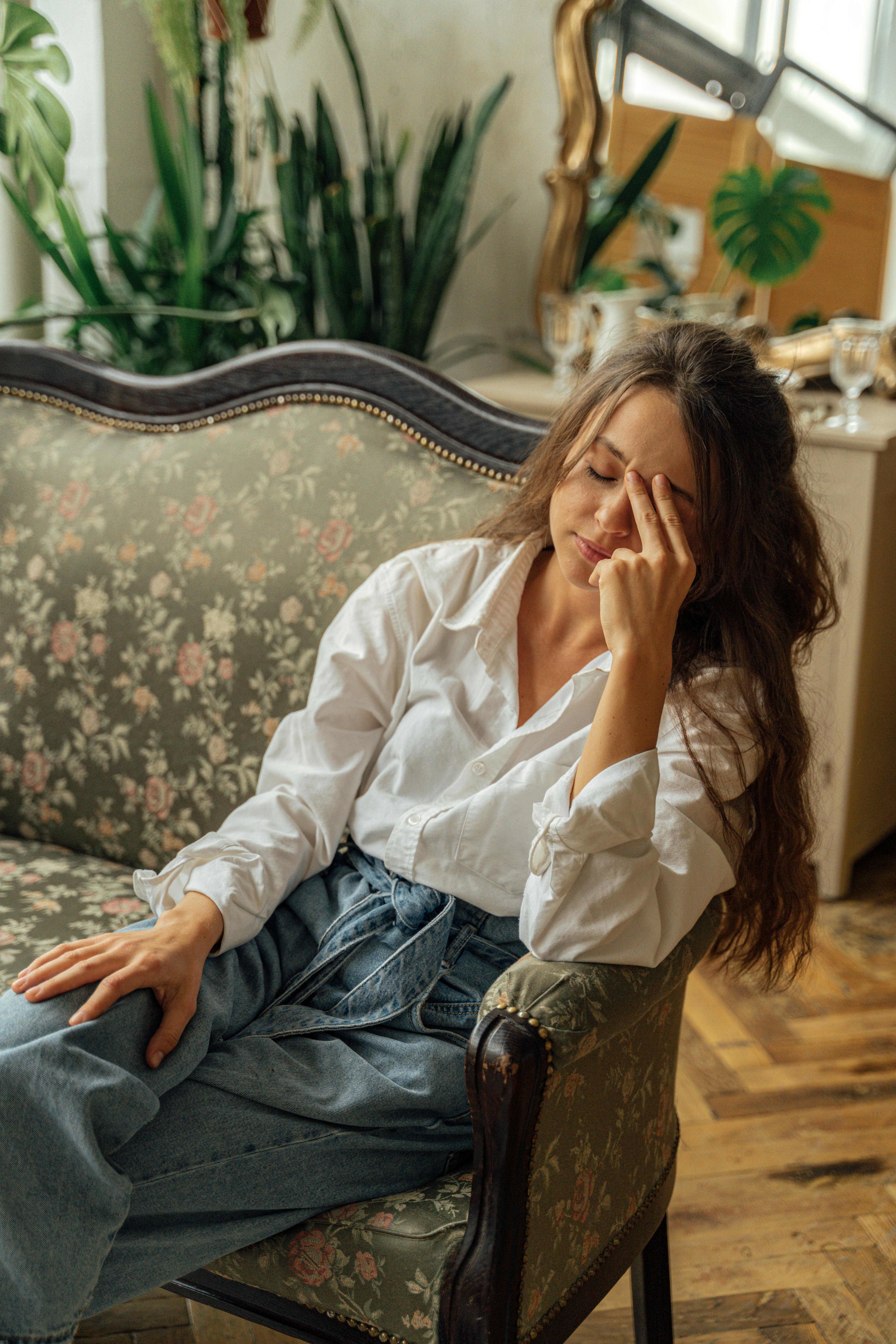 woman in white dress shirt and blue denim jeans sitting on couch