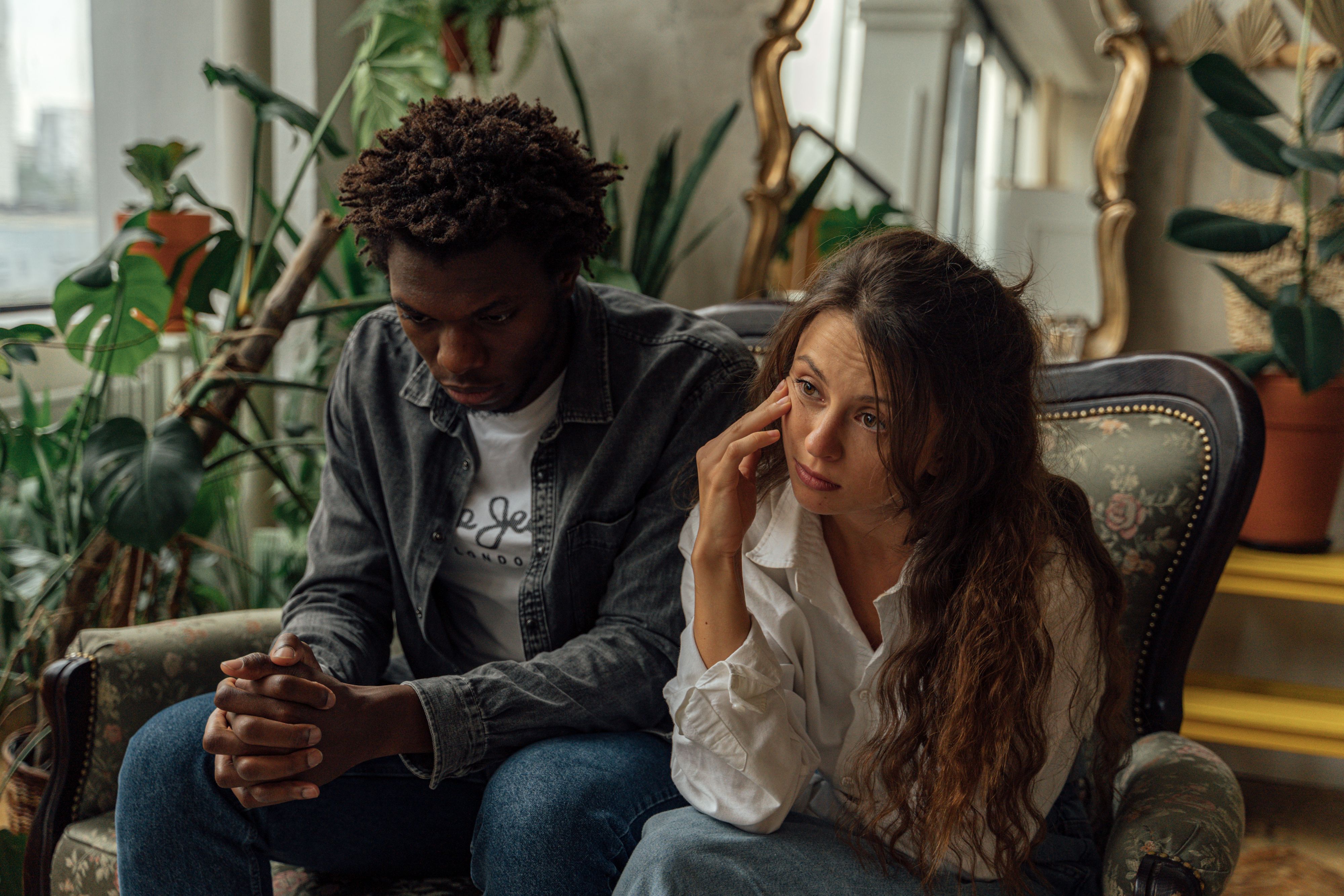 A couple sitting together thoughtfully in a naturally lit home
