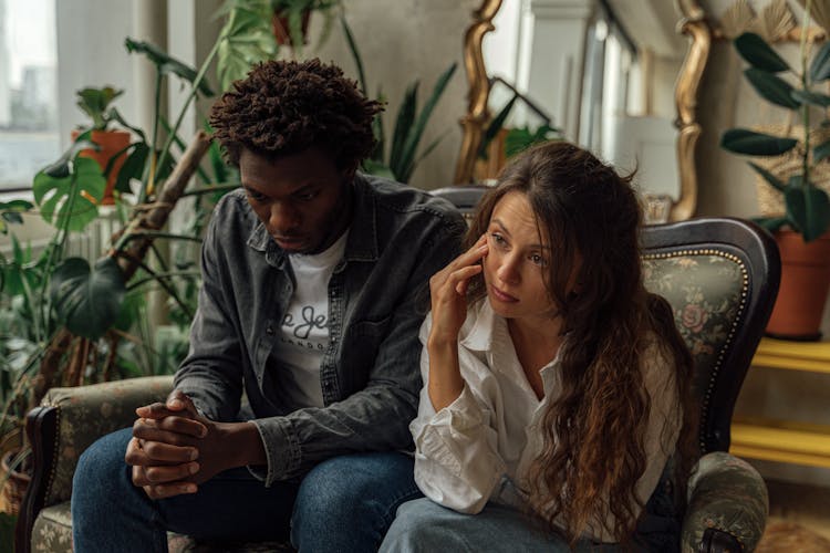 A Couple Sitting Next To Each Other On A Couch