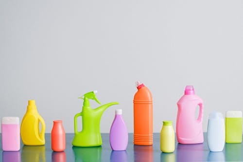 Free A vibrant assortment of cleaning product containers arranged on a reflective surface, perfect for household sanitation themes. Stock Photo
