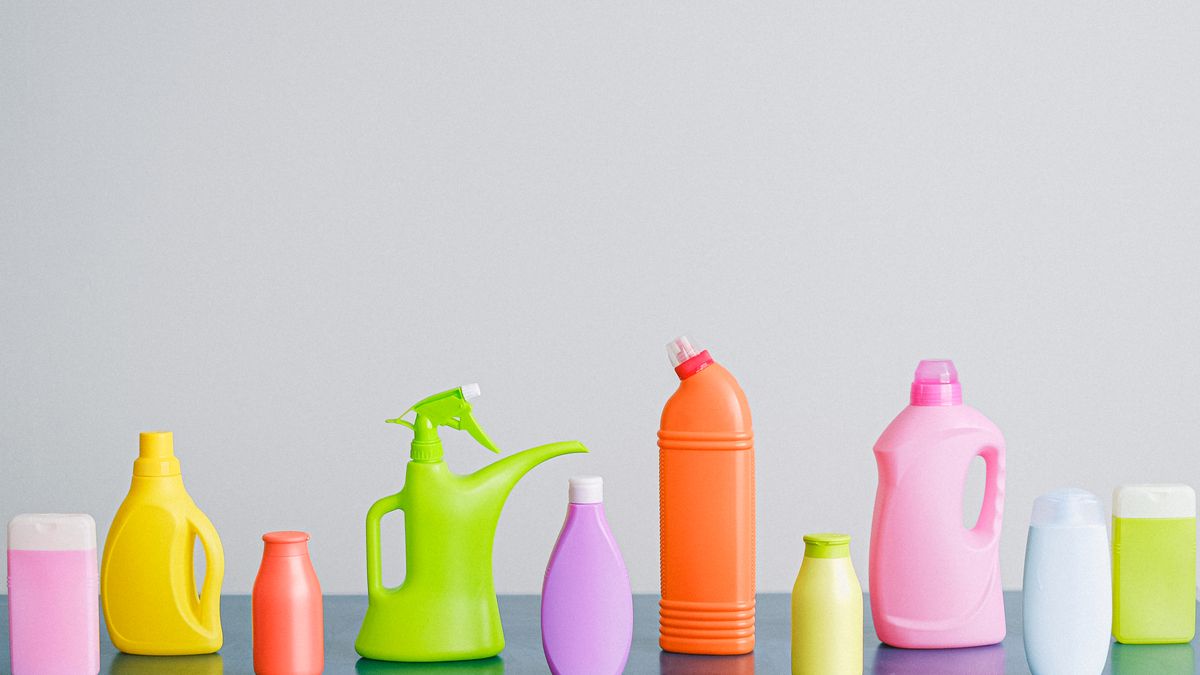 Frascos coloridos de produtos de limpeza organizados lado a lado sobre uma superfície clara