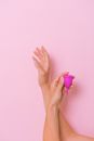 Crop faceless woman demonstrating pink menstrual cup