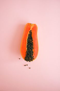 在柔和的粉色背景下，充满活力的木瓜被切成两半展示