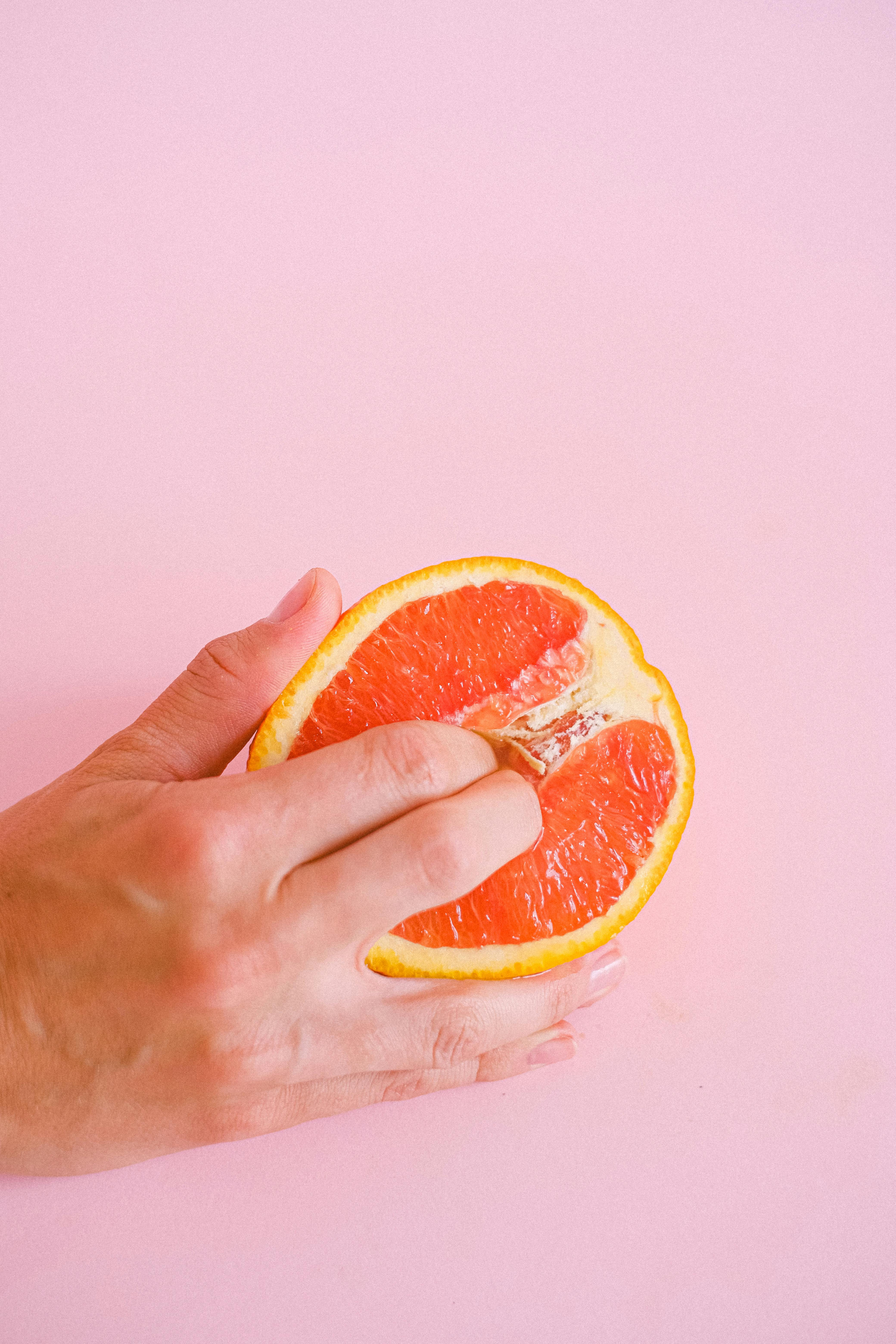 man putting his fingers in an orange