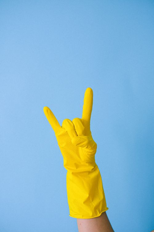 Free Crop anonymous person in yellow rubber glove demonstrating horn sign against blue background Stock Photo