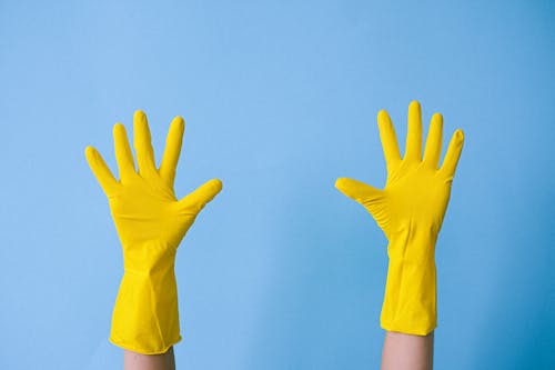 Crop unrecognizable person in rubber gloves raising arms