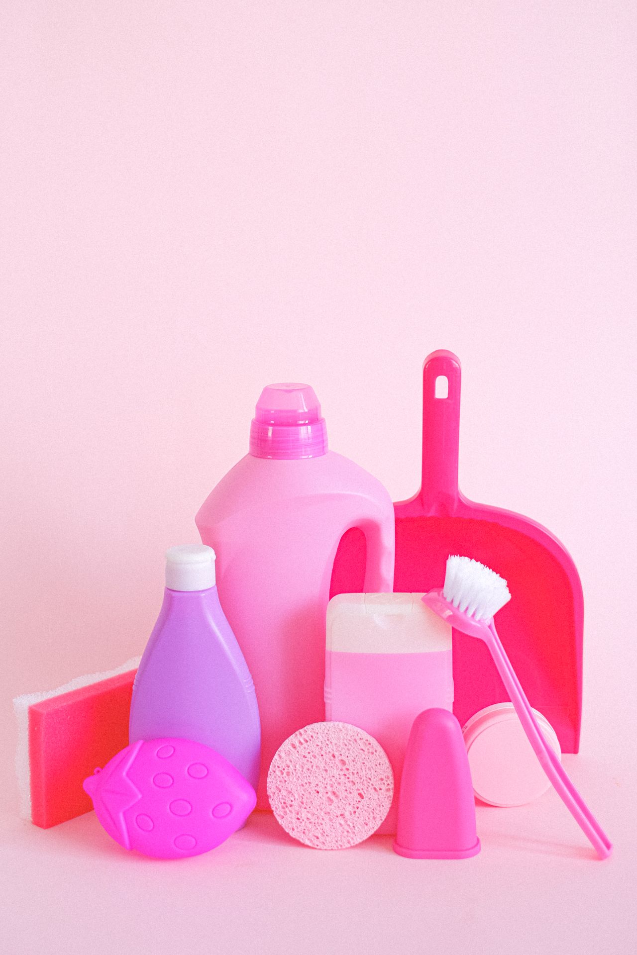 Starter cleaning supplies for a new apartment, including detergent bottles, sponges, a scrub brush, and a dustpan