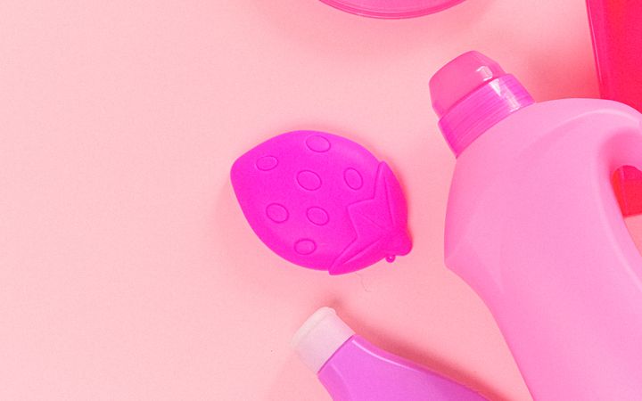 Top view of composed bottles and cup lid with rubber gloves on pink background
