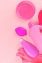 粉色背景上，组合瓶子和杯盖的顶视图带有橡胶手套