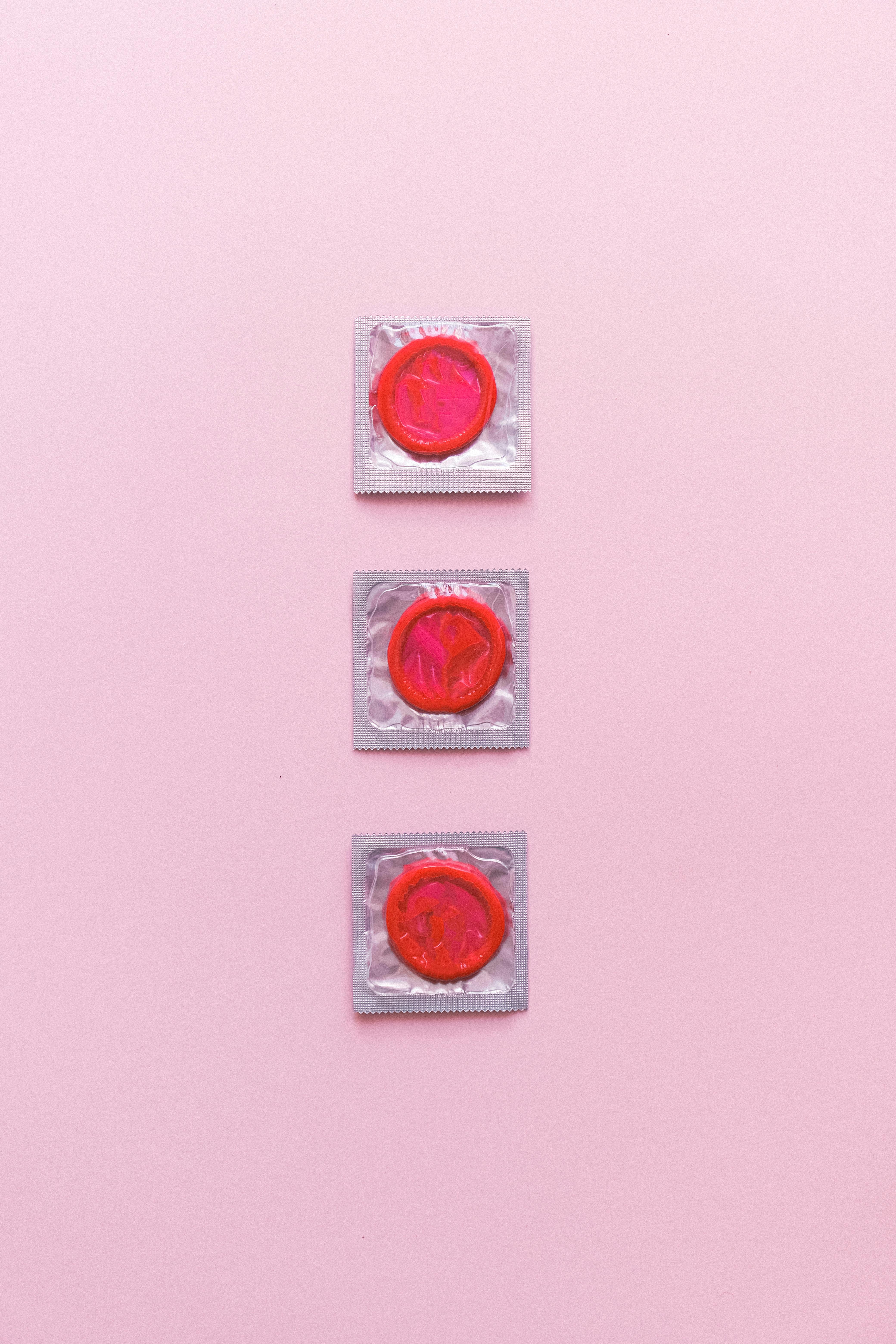 composition of red condoms on pink background