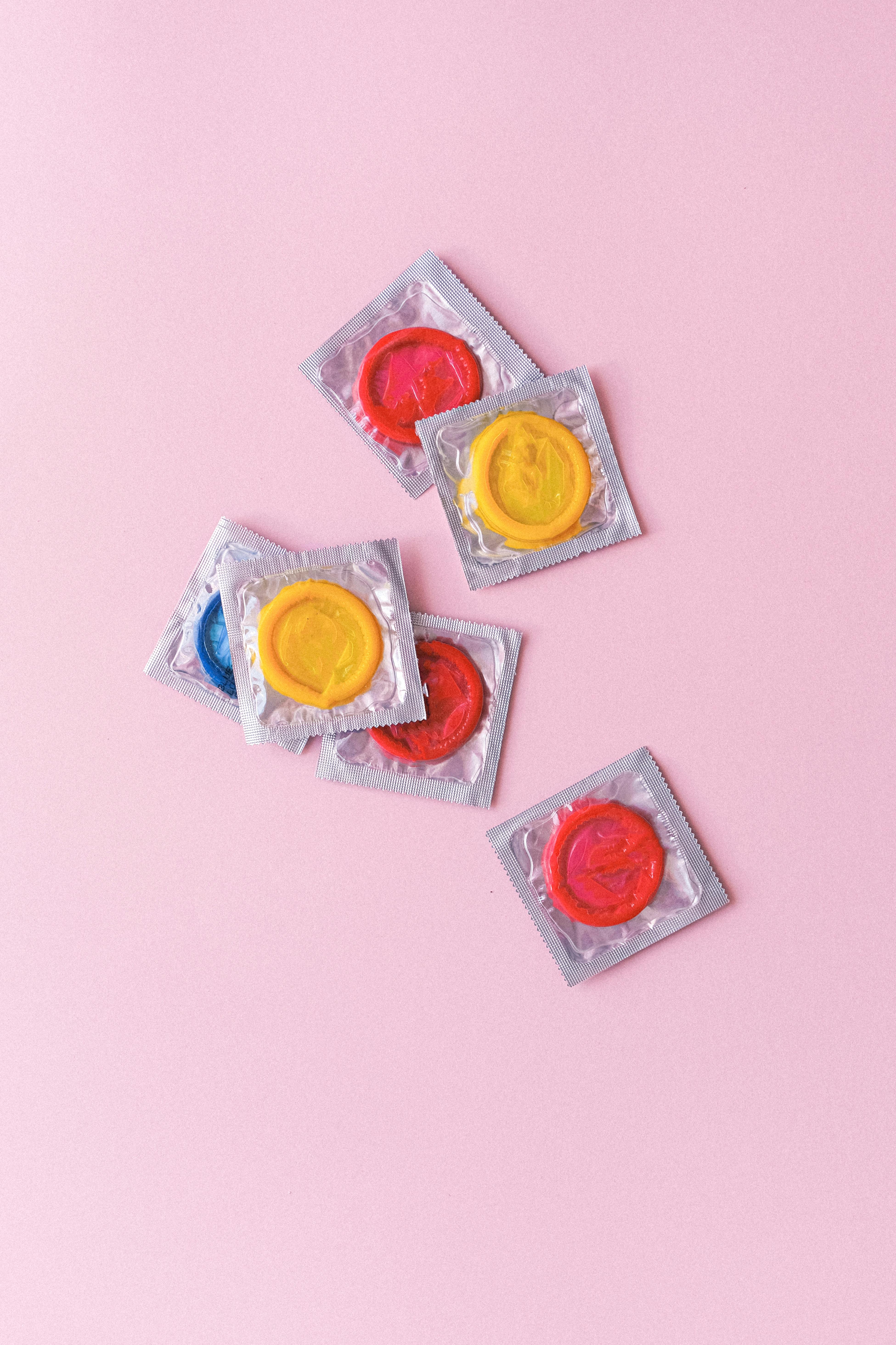 multicolored condoms heaped on pink background