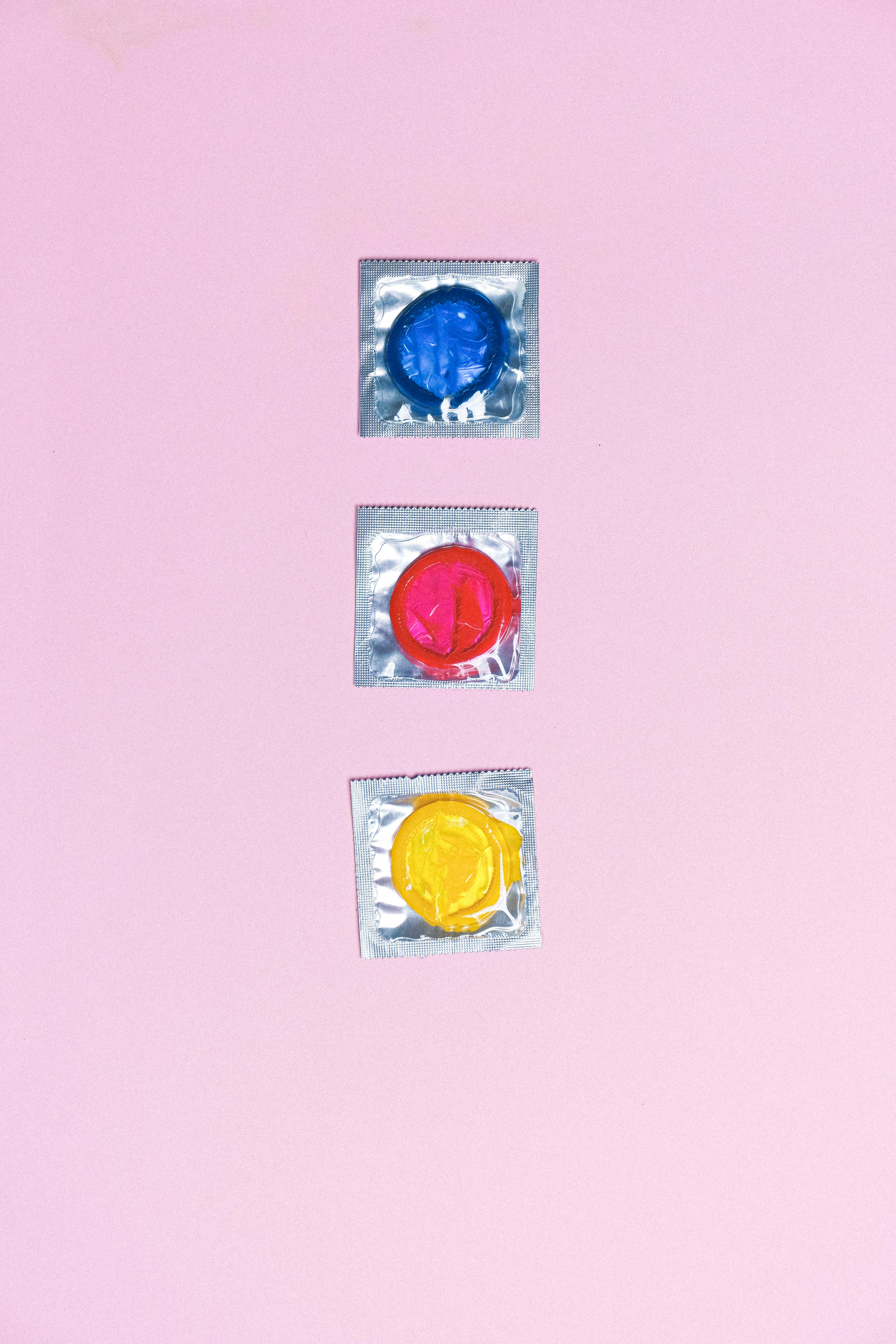 collection of colorful condoms on pink background