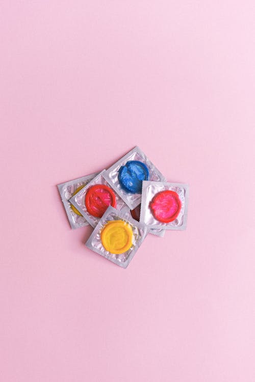 Multicolored condoms heaped on pink table